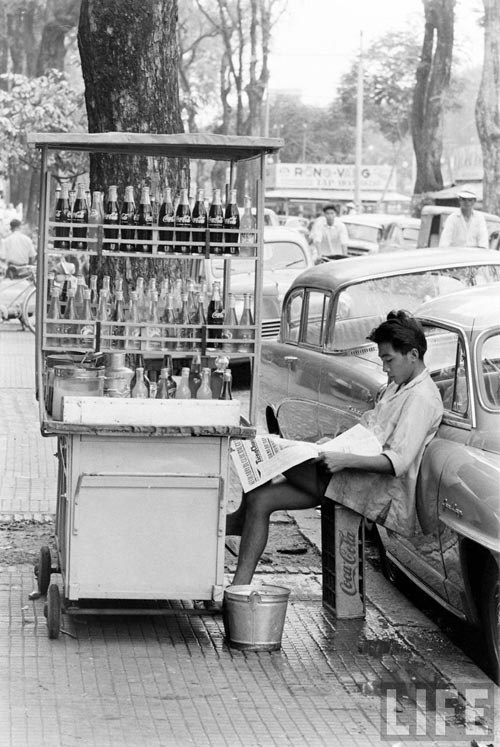 Cậu bé bán nước lấy khay nước ngọt làm ghế ngồi