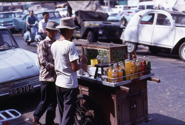 Xe đẩy bán rau má, nước ngọt. Có thể thấy người bán đang chặt đá, kế bên là thanh gỗ để làm đá bào (dành cho món xi rô đá bào mà học sinh rất yêu thích)