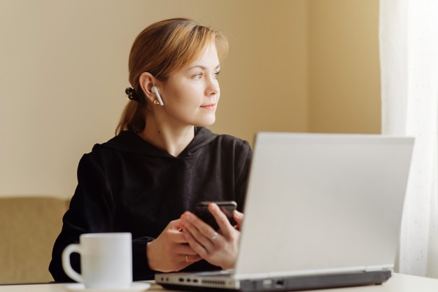 Woman using laptop and mobile phone for his remote work at home Free Photo