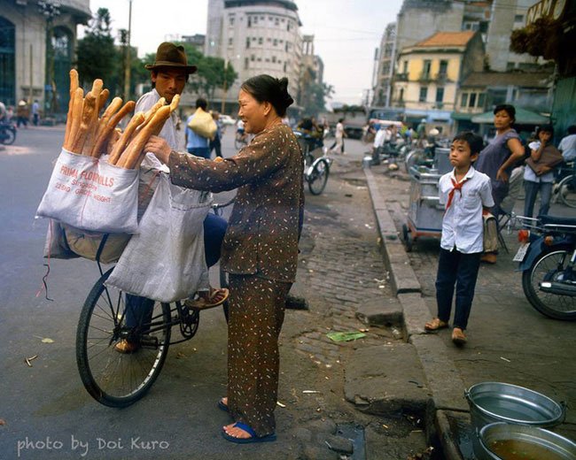 Cụ bà hớn hở mua bánh mì gần ngã tư Hồ Tùng Mậu – Hàm Nghi, 1989.