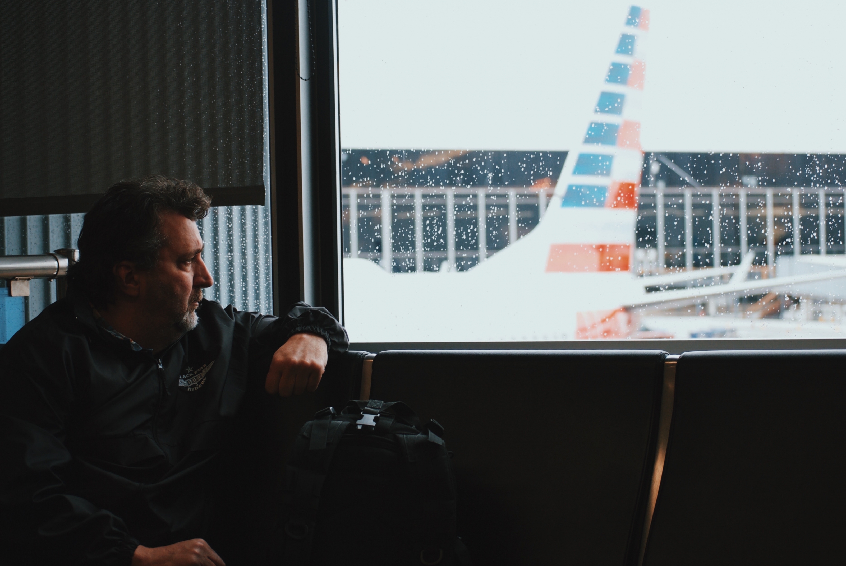 man sitting in airport watching airplane during daytime